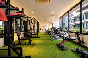 A gym with various exercise equipment, including weight machines and cardio machines, on a green floor.