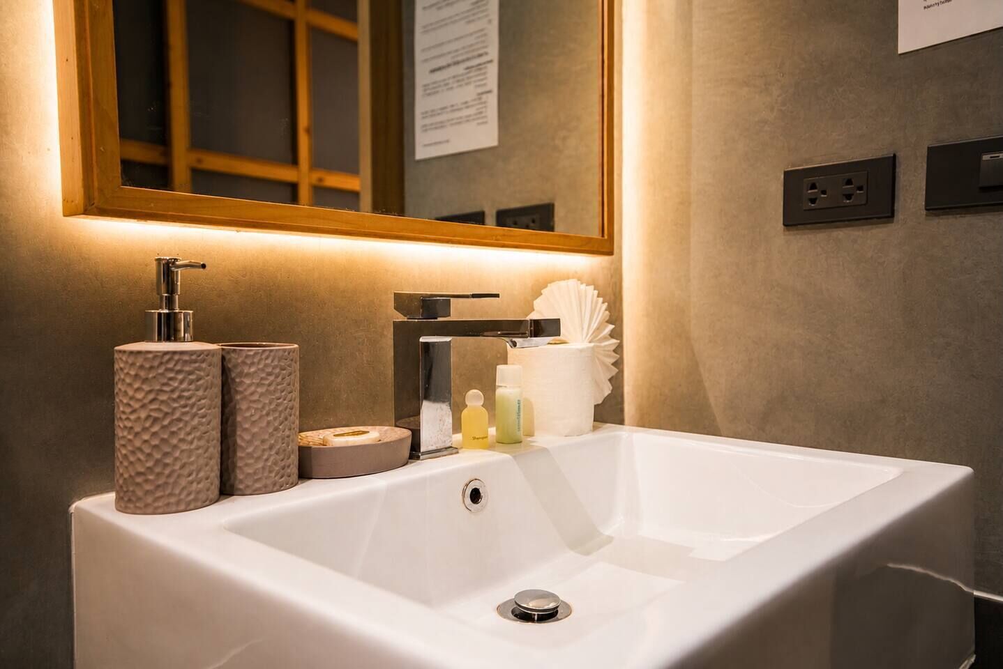 Ein Badezimmer mit weißem Waschbecken, einem Spiegel und Toilettenartikeln.