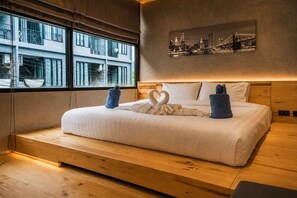 Una habitación de hotel moderna con una cama grande, vistas a la ciudad y suelo de madera.
