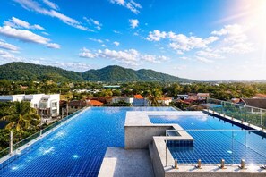 A rooftop infinity pool with a view of a mountainous landscape and residential buildings. - Studio Aira| Rooftop Pool | relife naiharn beach (Karon)