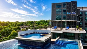 A modern building with a rooftop pool and lounge area, surrounded by greenery. - Studio Aira| Rooftop Pool | relife naiharn beach (Karon)