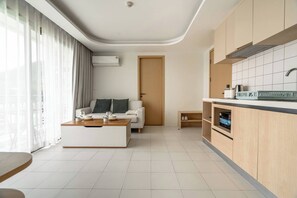 Een moderne woonkamer met een bank, salontafel en een keukenhoek met kastjes en een aanrecht.
