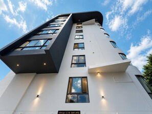 A modern building with a flat facade, multiple windows, and a sign indicating '2.1 M. HEIGHT LIMITED'.