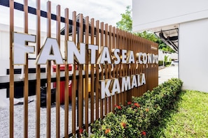 A sign for FANTASEA CONDOMINIUM KAMALA with a modern design and a view of the parking area.