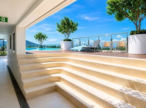 A set of outdoor stairs leading to a terrace with a pool, lounge chairs, and potted plants.