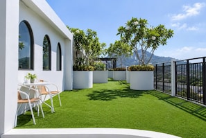 Eine moderne Außenpatio mit künstlichem Rasen, weißen Pflanzgefäßen und einem schwarzen Zaun.