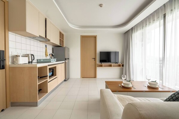 A modern kitchen with built-in appliances, a dining area with a table set for two, and a TV mounted on the wall.