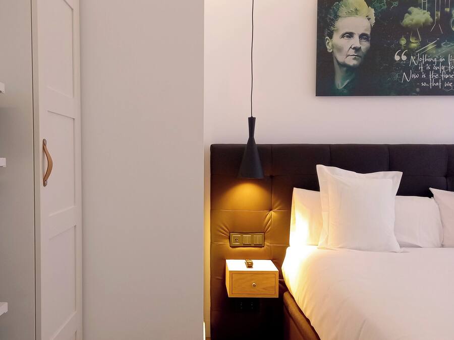 Una habitación de hotel con una cama, una mesita de noche y un estante con microondas.