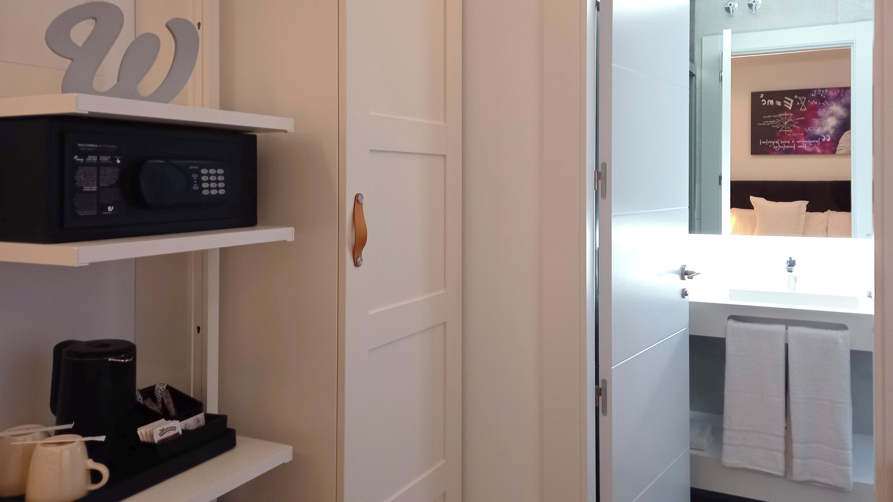 A hotel bathroom with a white sink, a mirror, and a towel rack.