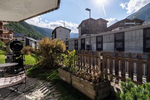 Un patio con mobiliario exterior, cerca de madera y montañas al fondo.