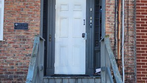 Edificio de ladrillo con una escalera de madera que conduce a una puerta blanca con el número 408.