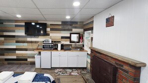 Una habitación de hotel compacta con kitchenette, un televisor de pantalla plana, un microondas pequeño y un lavamanos.