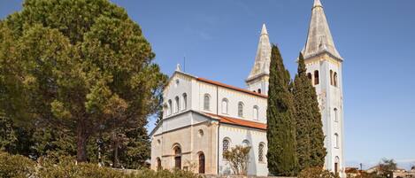 A historic church with two towers, surrounded by well-maintained gardens and trees.
