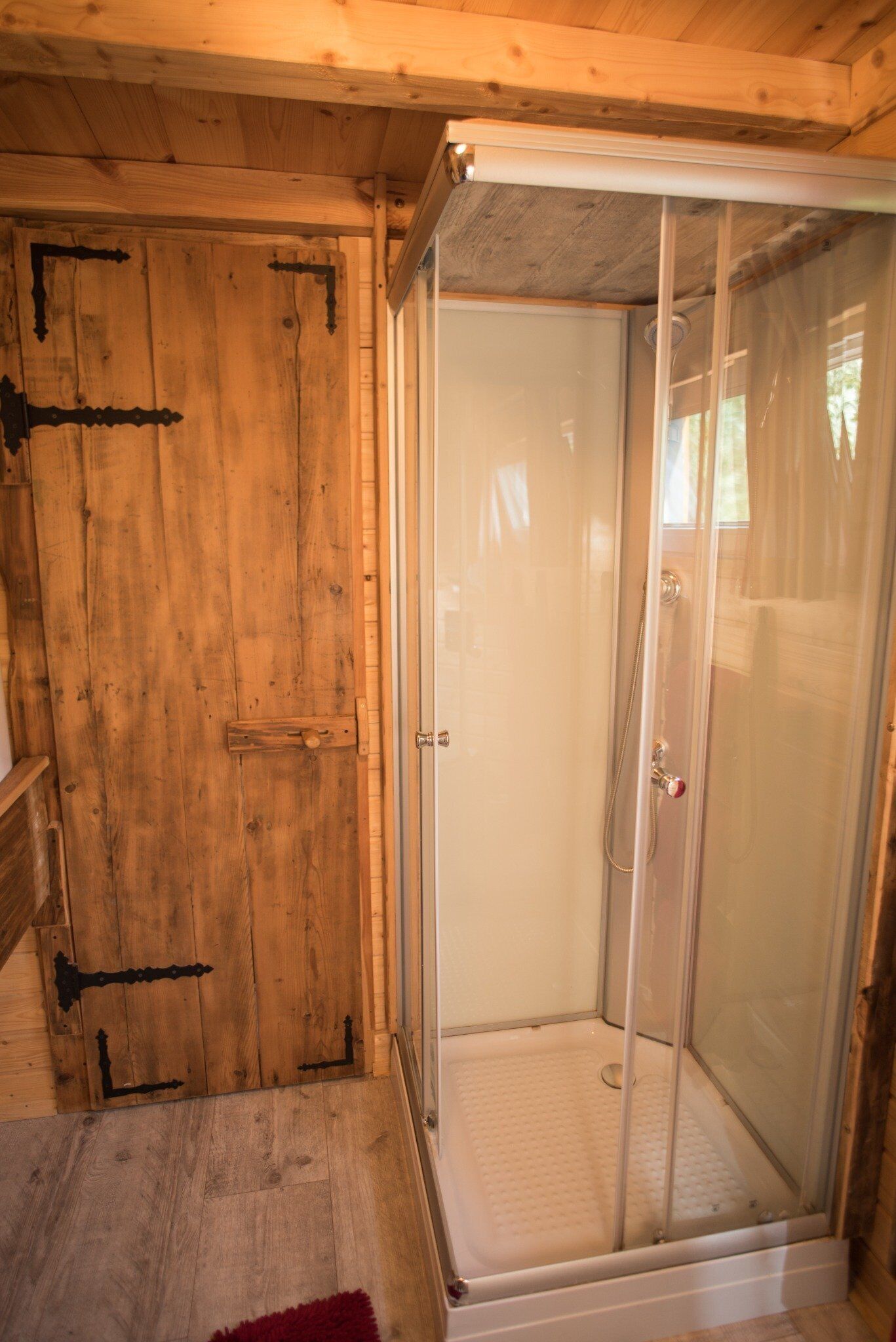 L'intérieur d'un chalet en bois, avec une douche séparée par des parois en verre.
