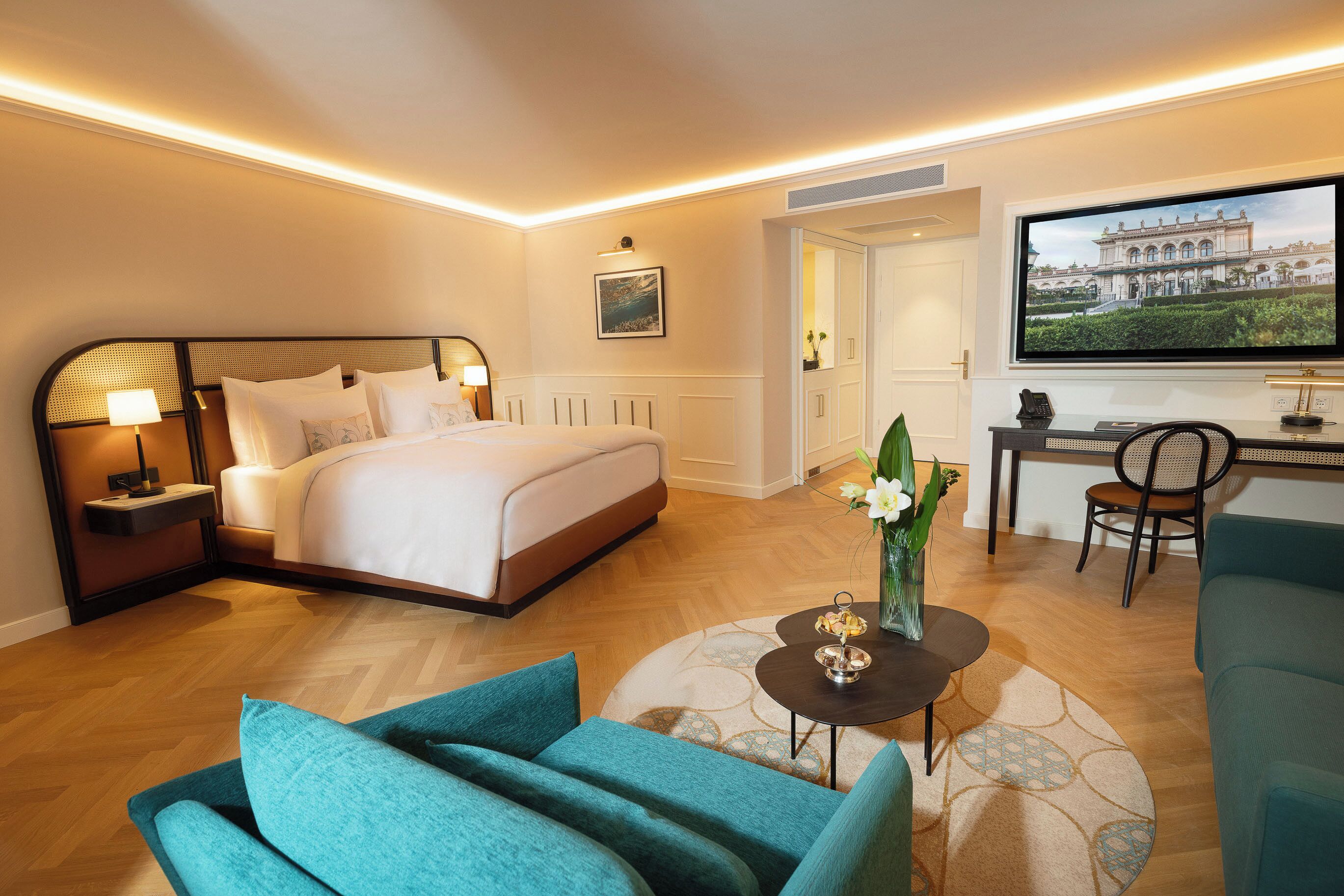 A hotel room with a bed, a desk, a TV, and a sofa.