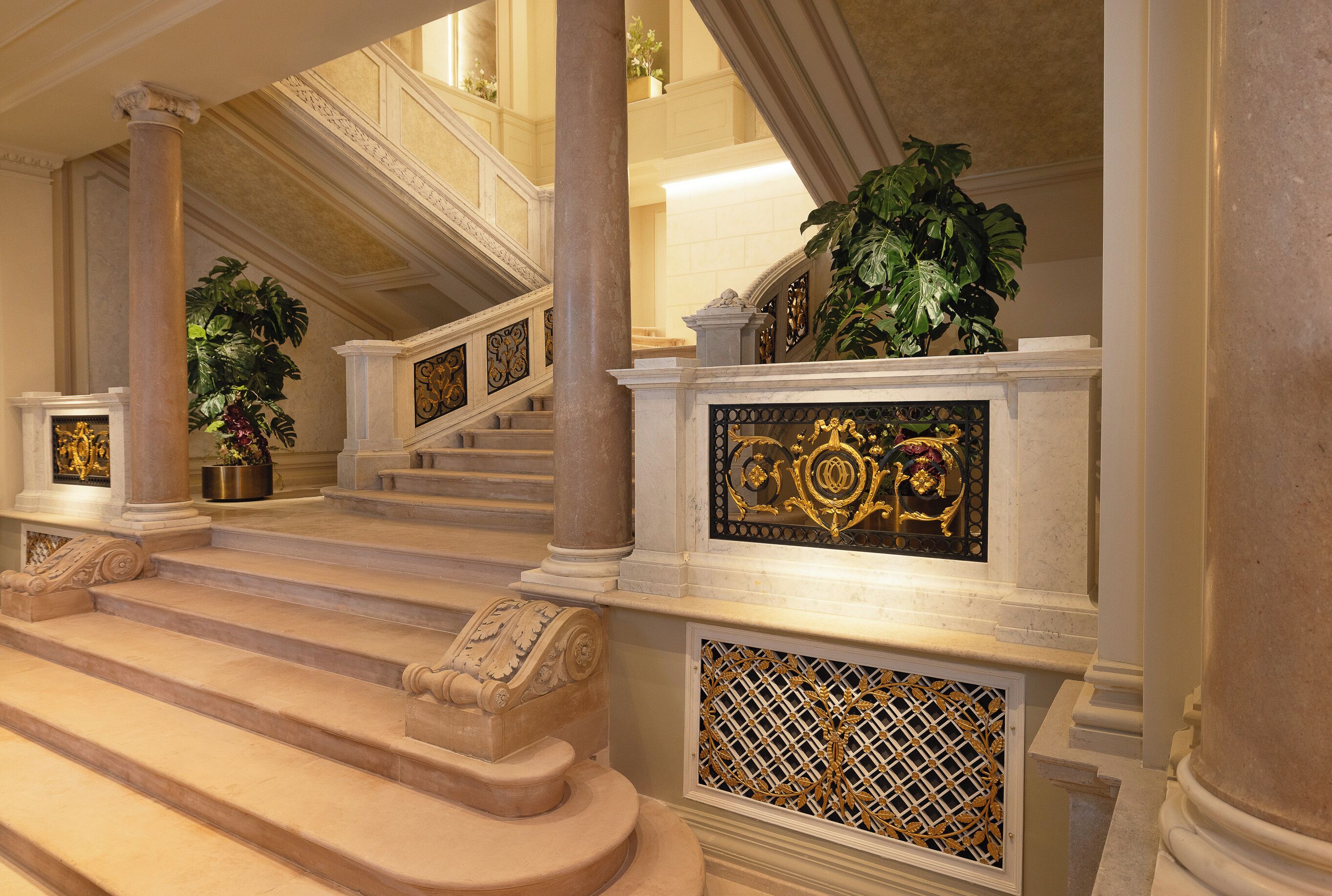 A grand staircase with ornate balustrades, columns, and decorative panels.