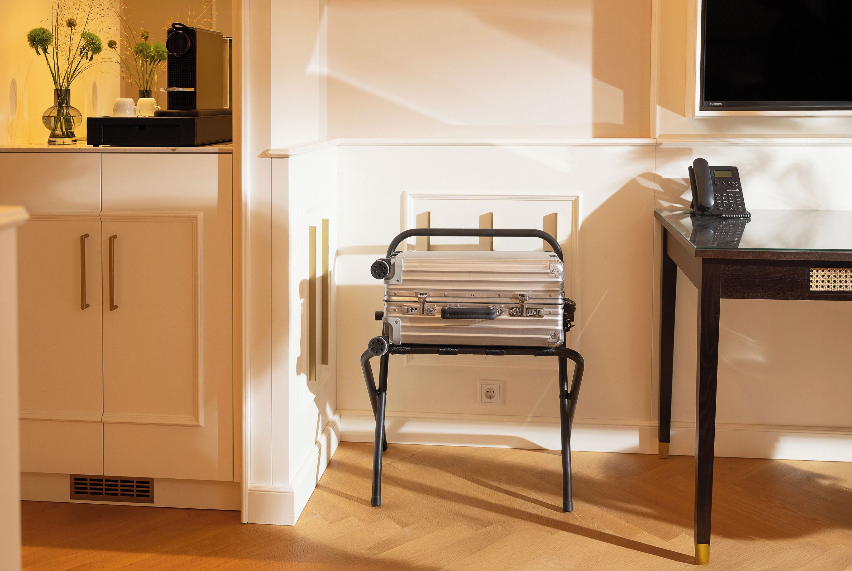 Una habitación pequeña con kitchenette, una mesita y un teléfono, y un radiador.