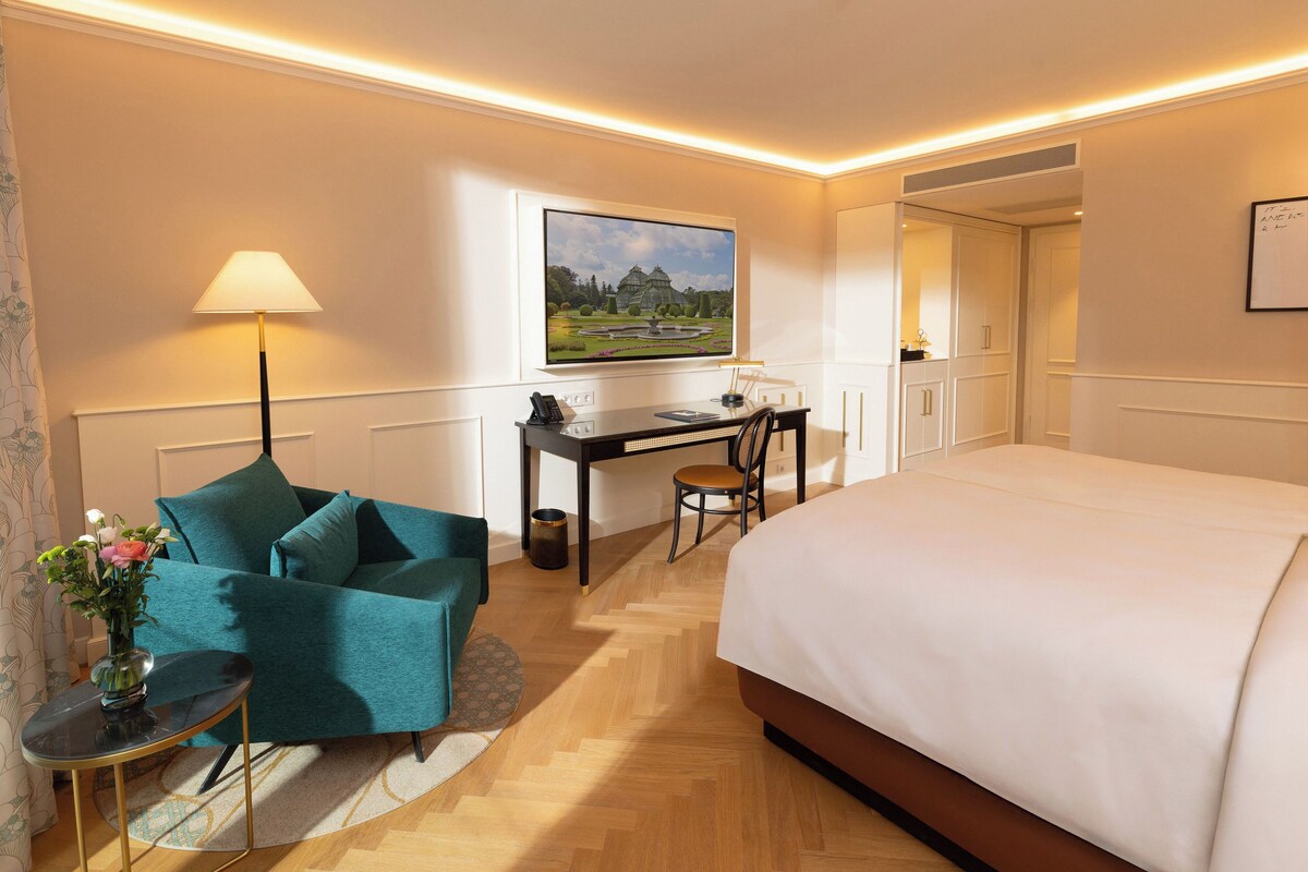 A hotel room with a bed, desk, chair, and a TV mounted on the wall.