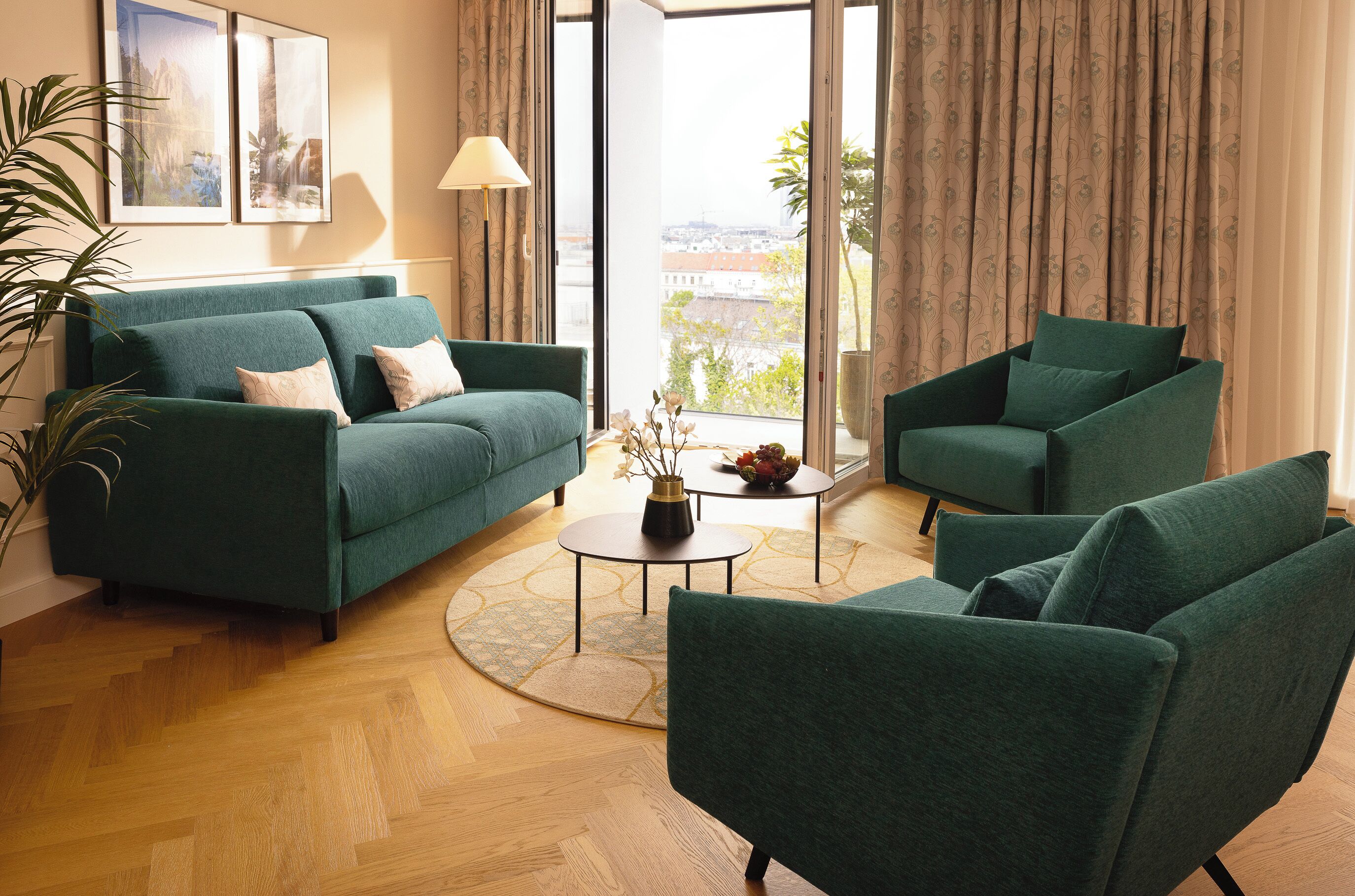 A living room with a sofa, armchairs, a coffee table, and a view through large windows.