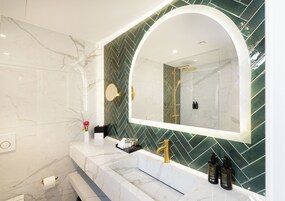 Un bagno moderno con un lavandino in marmo, uno specchio grande e un rivestimento verde a motivi a spina di pesce.
