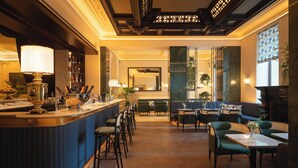 A bar area with a counter, stools, and a seating area with tables and chairs. - EST Hotel Palais Chotek NEW OPENING (Vienna)