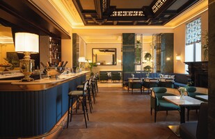 Uma área de bar com balcão, banquetes e espaço de estar com mesas e cadeiras.