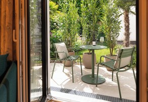 Een terras met een ronde tafel, twee stoelen en potplanten.
