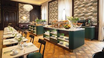 Un restaurante con mesas largas, sillas, una zona de bar y un suelo estampado.