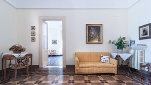 A living room with a patterned floor, a sofa, a table with a basket, and a chair.