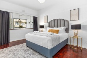A modern bedroom with a large bed, a view through a sliding door, and a small bedside table with a lamp. - 1 Plomarion (Cape Town)
