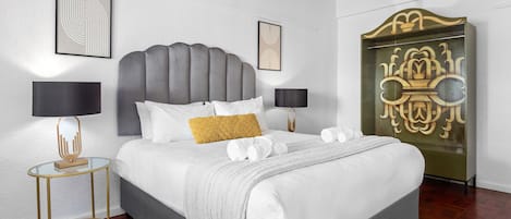 Un dormitorio moderno con una cama grande, dos mesitas de noche y un aparador decorativo.