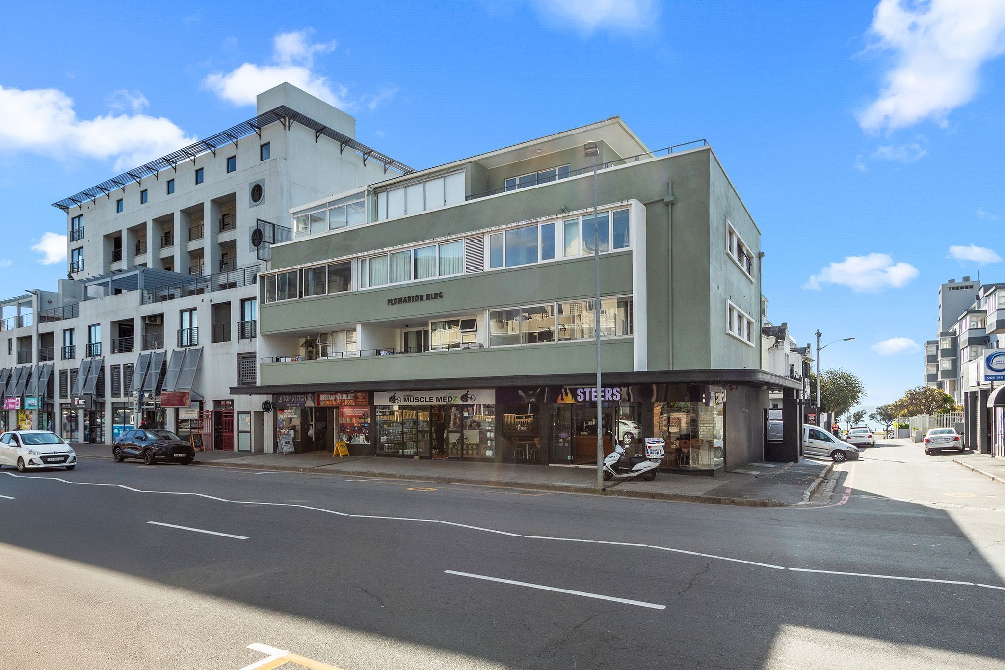 A multi-story building with a ground-floor storefront, including a muscle med and a steers store.