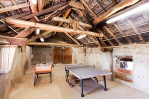 Ein Zimmer mit Tischtennisplatte, Kicker und sichtbaren Holzbalken.