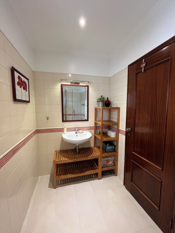 A bathroom with a sink, mirror, and wooden shelves.