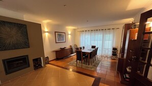 A spacious living area with a dining table, chairs, a fireplace, and a bookshelf. - Spacious villa with garden and barbecue, near Serra de Sintra, beach and Cascais (Alcabideche)