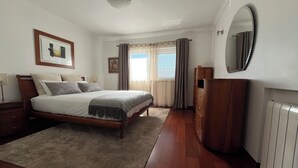 A bedroom with a bed, a dresser, a mirror, and a radiator. - Spacious villa with garden and barbecue, near Serra de Sintra, beach and Cascais (Alcabideche)