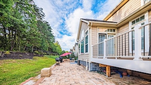 A patio with a brick pathway leading to a house with a covered outdoor seating area.