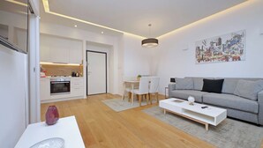 Un salon moderne avec un canapé gris, une table basse blanche et un coin repas comprenant une table et des chaises blanches.