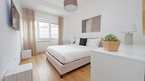 Une chambre moderne avec un grand lit, une table de chevet, une lampe et une plante en pot.