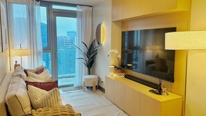 Un salon moderne avec un canapé, un téléviseur et une petite table agrémentée d’objets décoratifs.