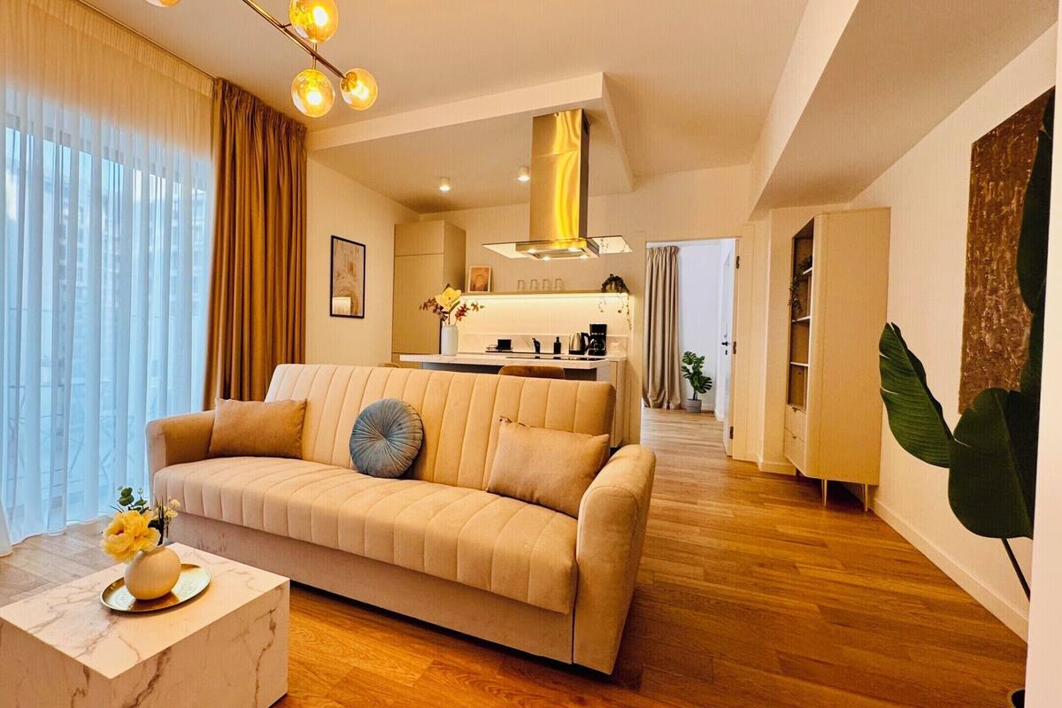 A modern living room with a sofa, a coffee table, and a kitchen in the background.
