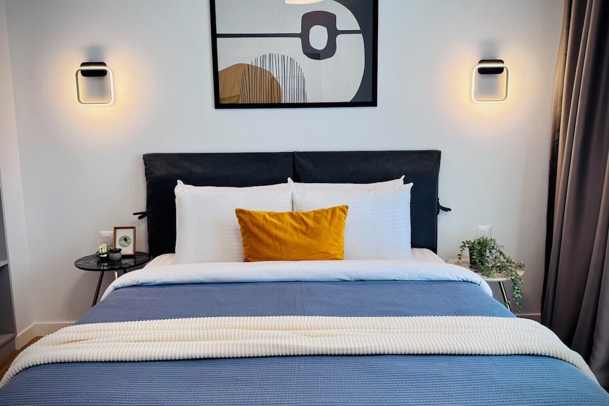 A hotel room with a bed, bedside tables, a wall-mounted artwork, and a curtain.