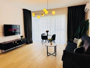 A modern living room with a flat-screen TV, a round coffee table, and a sofa. - Feel at Home in Bucharest (Bucharest)