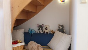A cozy room with a sloped ceiling, a blue sofa, and a pig plush toy on the floor. - Family-Friendly Holiday Home 'Märchengarten Fischer Un Sin Fru' (Putbus)