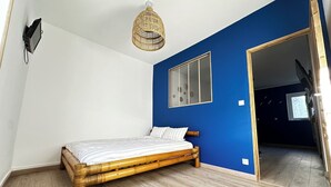 Una camera da letto con un letto, una TV a parete, una lampada a soffitto e una finestra.