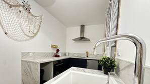 Una cucina moderna con un piano di lavoro in marmo bianco, un lavello in acciaio inossidabile e una lavastoviglie compatta.
