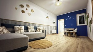 Un soggiorno moderno con un divano, un'area pranzo con tavolo e sedie, e decorazioni a parete.