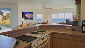 Une cuisine équipée d’une cuisinière, d’un four et offrant une vue sur l’océan grâce à de grandes fenêtres.