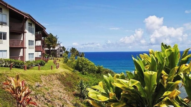 Un hôtel situé en bord de mer, doté de nombreux balcons, d’une végétation luxuriante et offrant une vue dégagée sur l’océan.