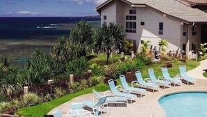 Un complexe hôtelier doté d’une piscine, de chaises longues et offrant une vue sur l’océan.